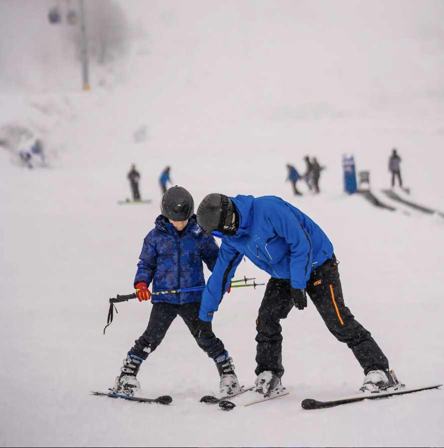 A person teaching a kid skiing