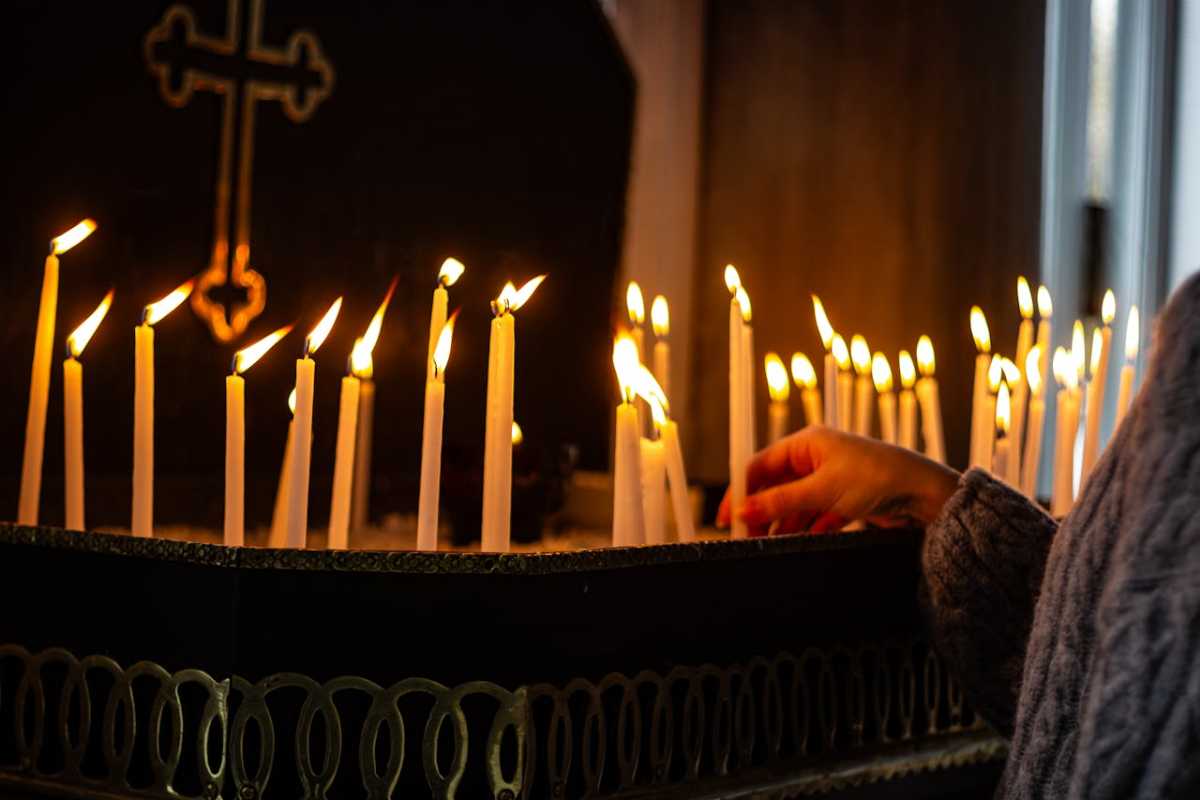 person putting candles in church